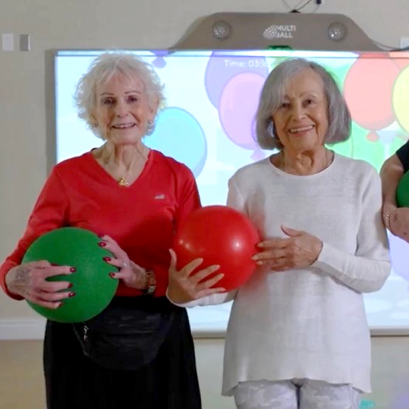 two women holding balls in front of Multi-Ball screen
