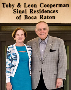 Toby and Leon Cooperman standing in front of Sinai Residences building entrance